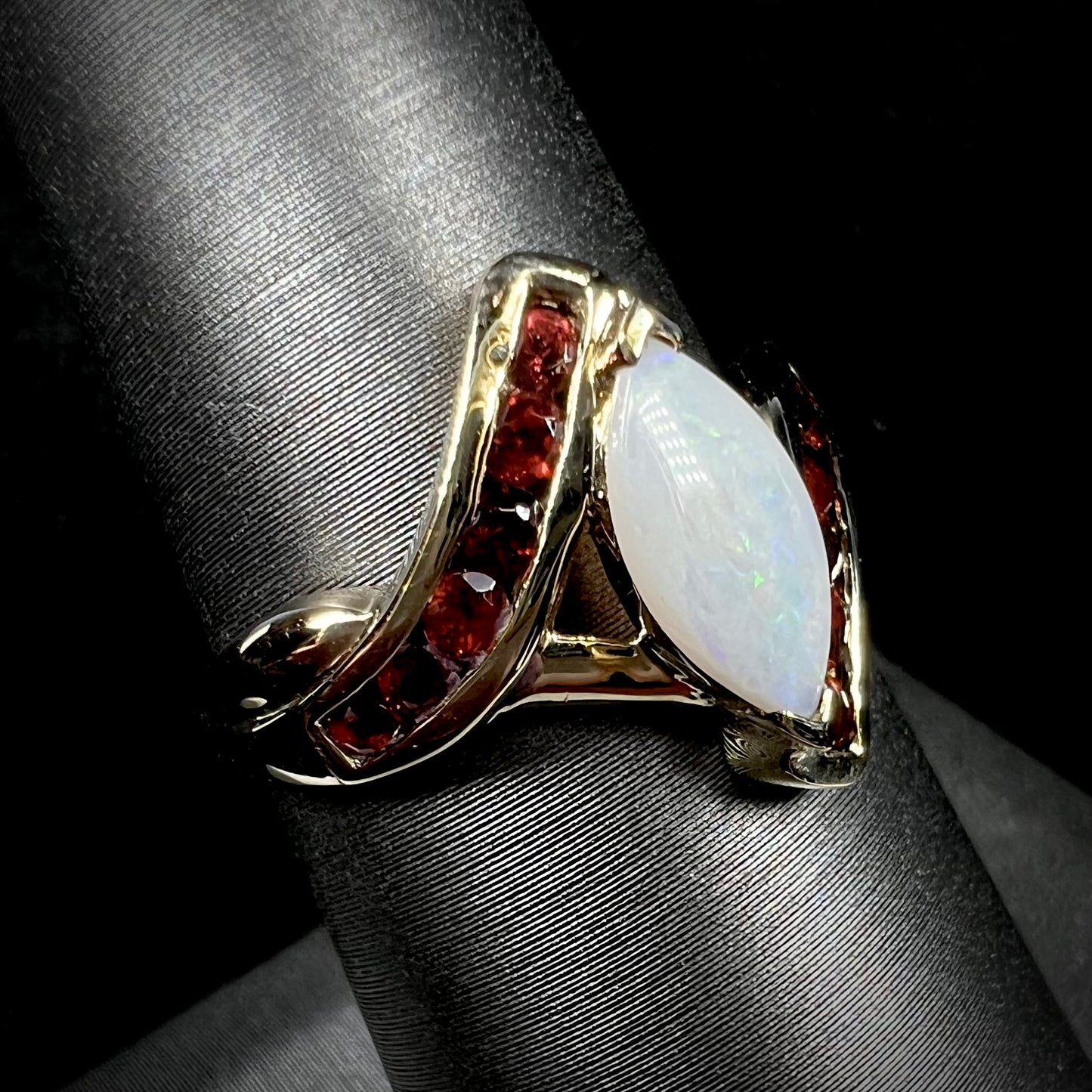 A marquise cut white opal ring.  The ring is accented with channel set reddish orange garnets.