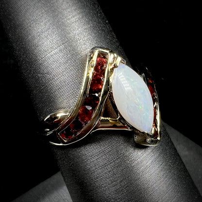 A marquise cut white opal ring.  The ring is accented with channel set reddish orange garnets.