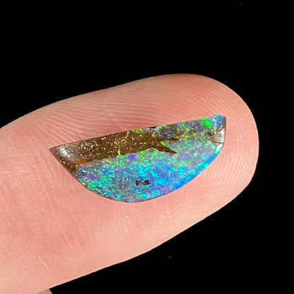 A freeform shaped boulder opal stone from Quilpie, Australia.  The opal has bright blue and green play of color.