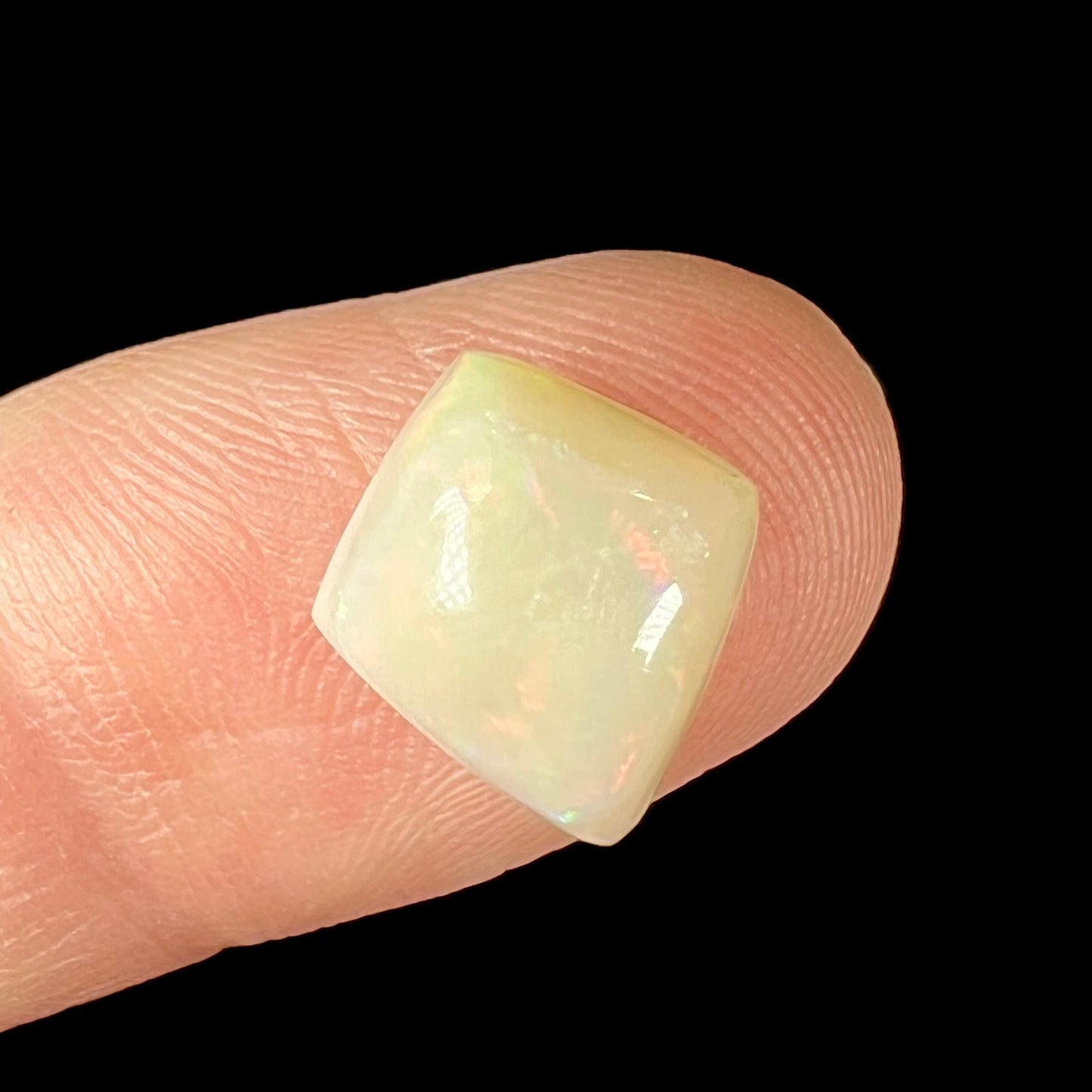 A loose, kite shaped white opal stone from Coober Pedy, Australia.  The stone has subdued red colors.