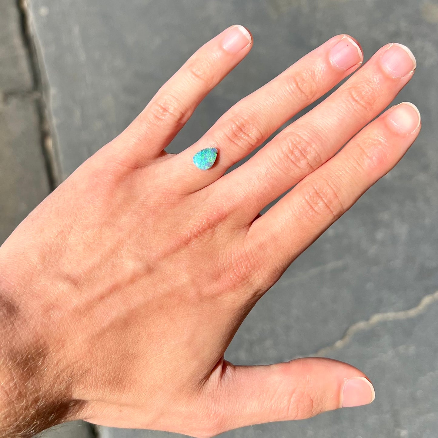 A loose, pear shaped black opal from LIghtning Ridge, Australia.  The opal shines blue and green colors.