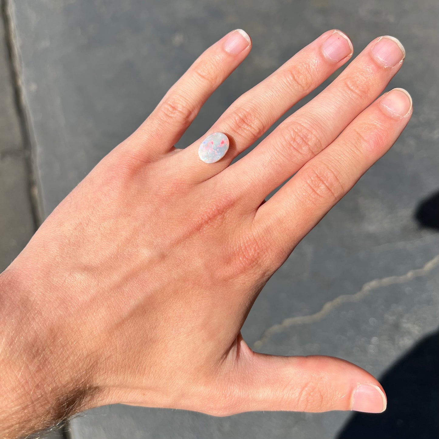 A loose oval cut opal stone from Lightning Ridge, Australia.  The opal shines pinkish red colors.