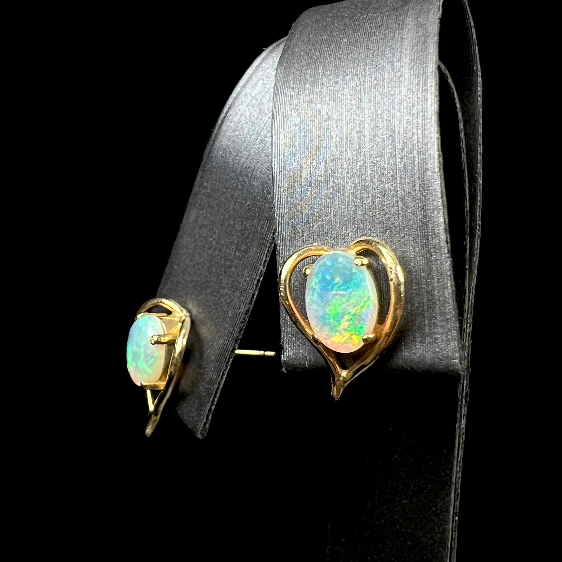 A pair of yellow gold, heart shaped stud earrings set with oval cabochon cut natural opal stones.