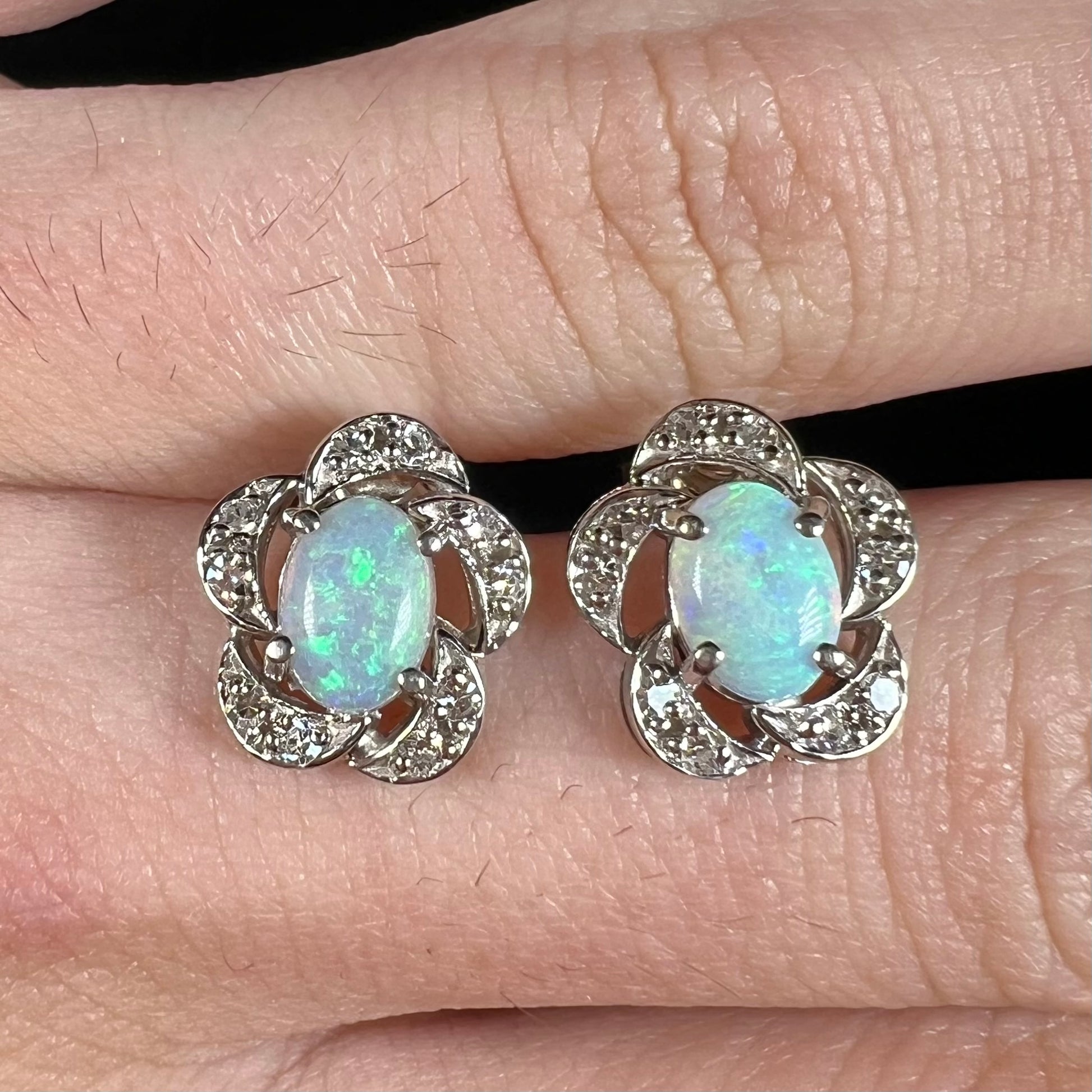 A pair of white gold flower stud earrings with diamonds mounted in the petals and opals set in the center.