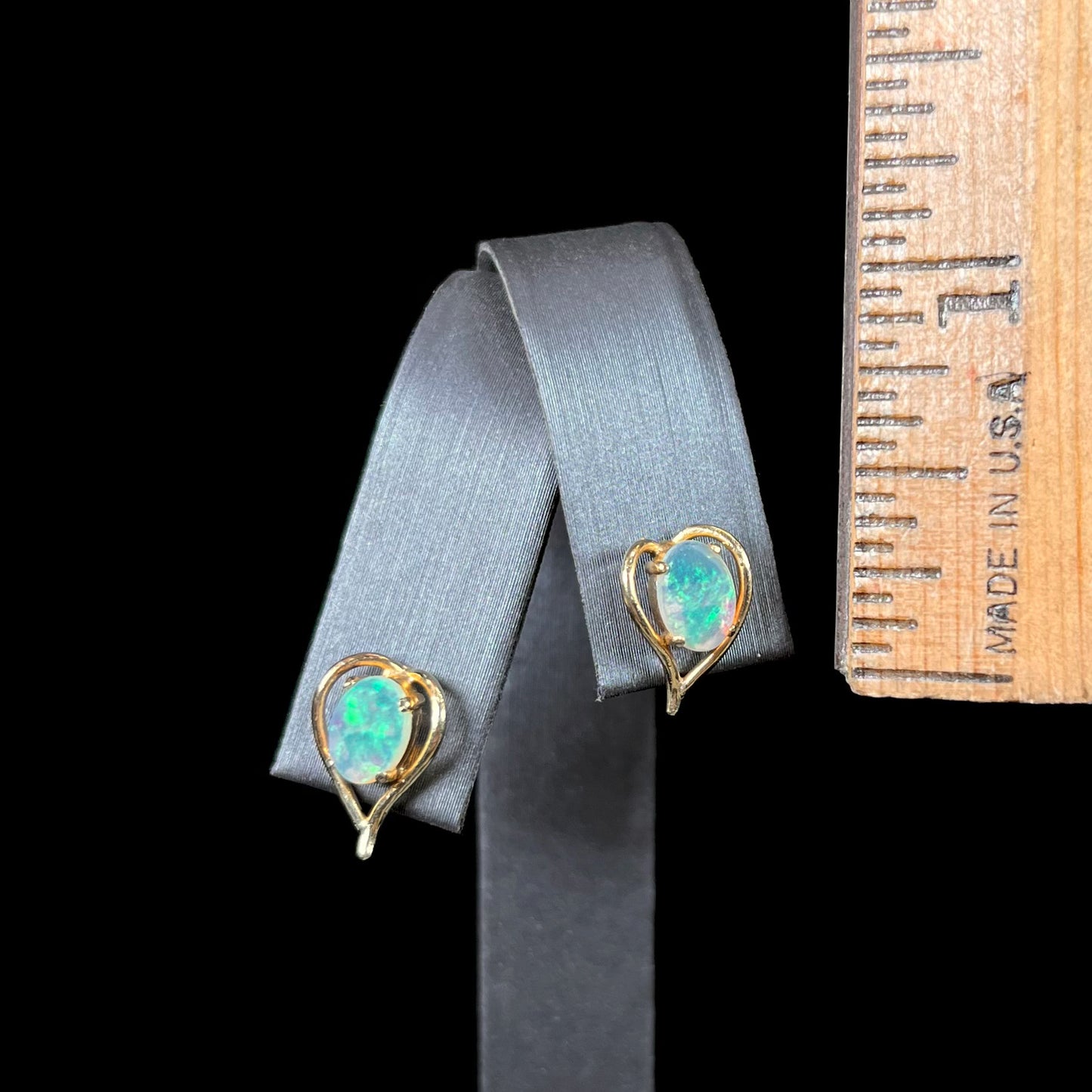 A pair of yellow gold, heart shaped stud earrings set with oval cabochon cut natural opal stones.