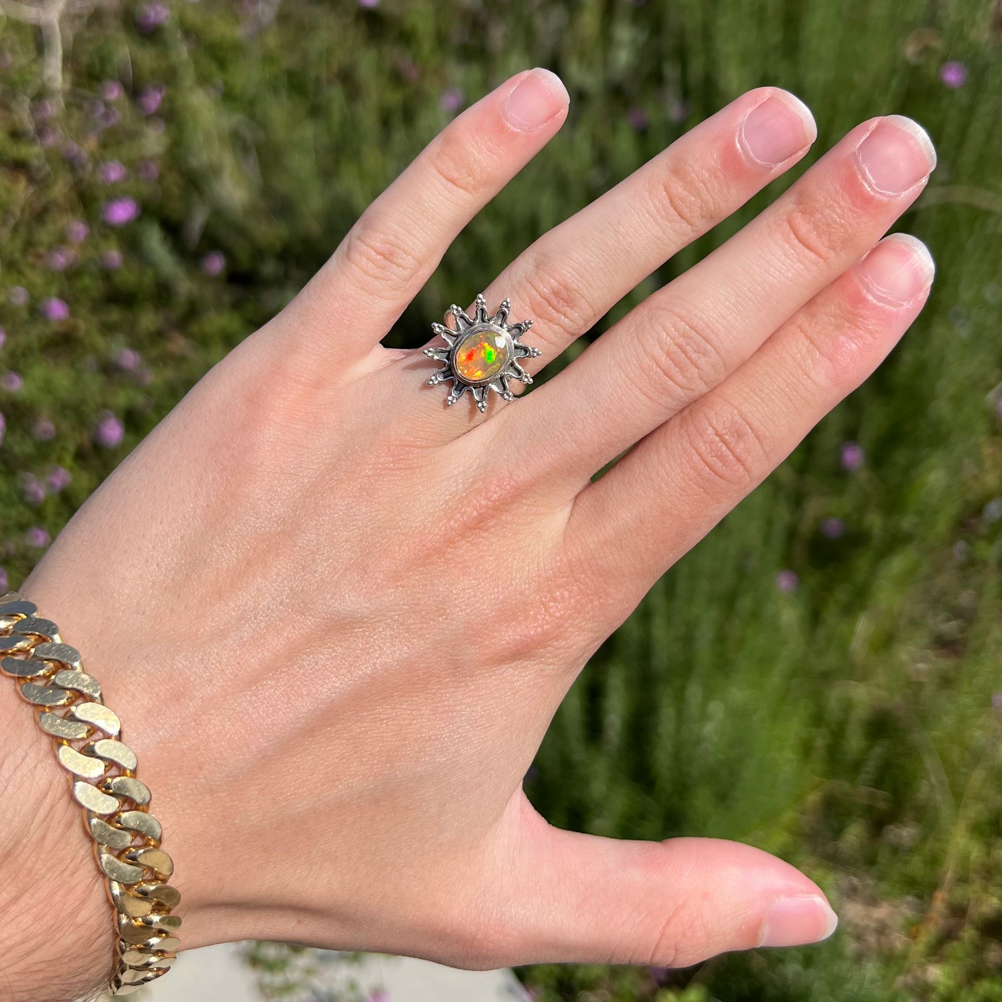 A sterling silver sunburst-style ring mounted with a faceted oval cut Ethiopian fire opal.