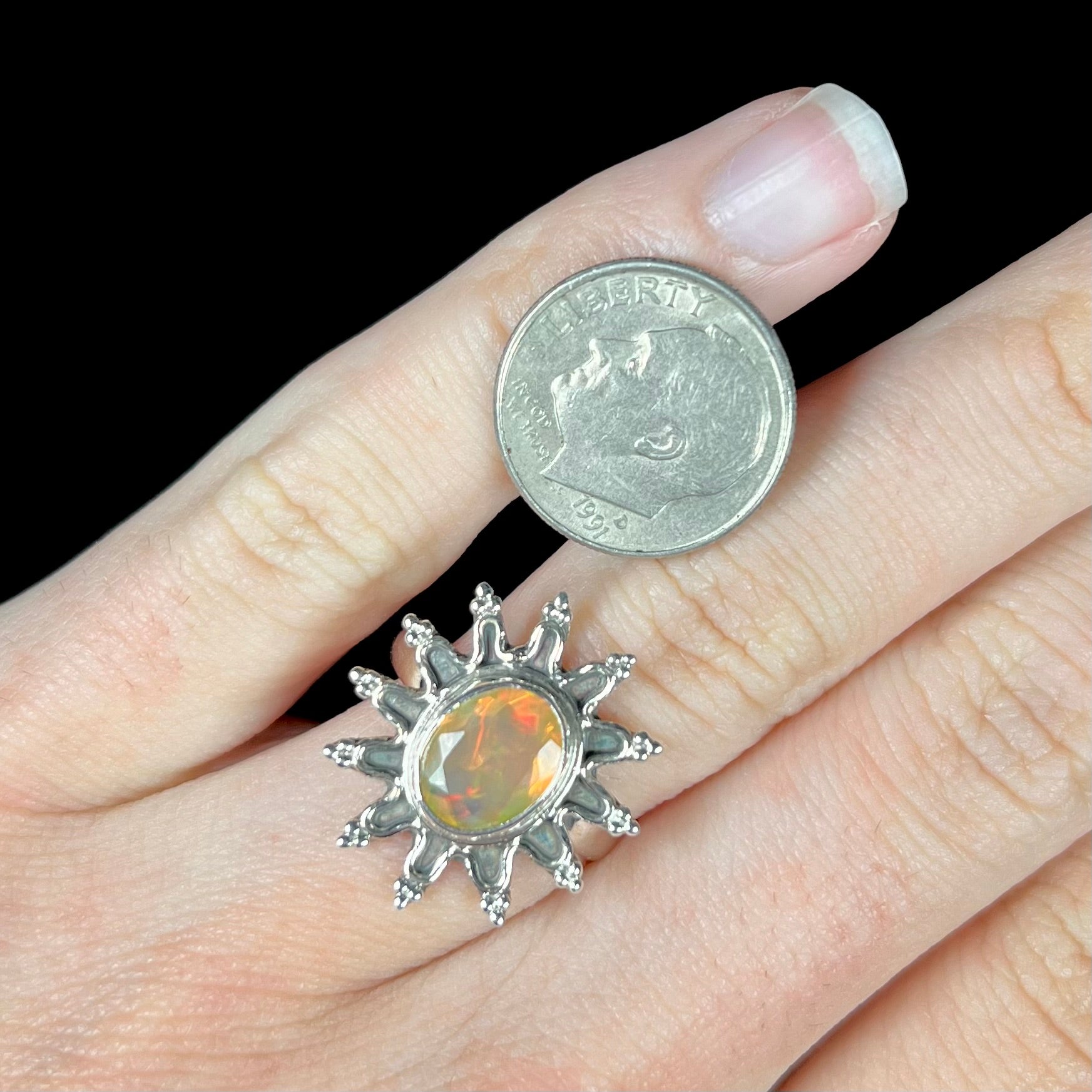 A sterling silver sunburst-style ring mounted with a faceted oval cut Ethiopian fire opal.