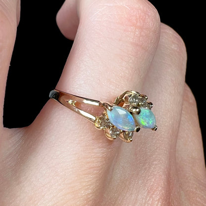 A yellow gold ring mounted with two marquise cut opals and accented with six round diamonds.