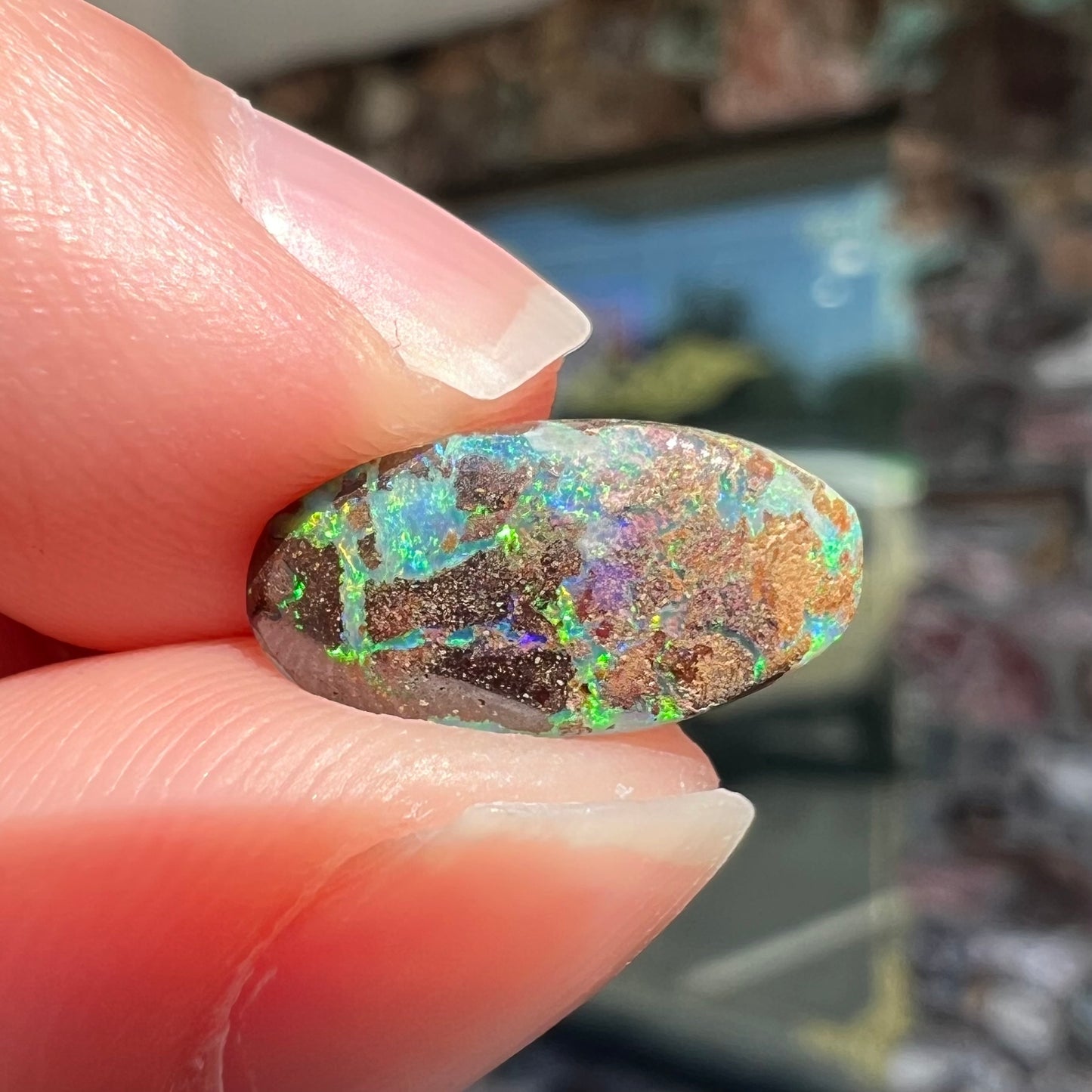 A loose, oval cabochon cut Koroit boulder opal stone.  The opal has a bright green color.