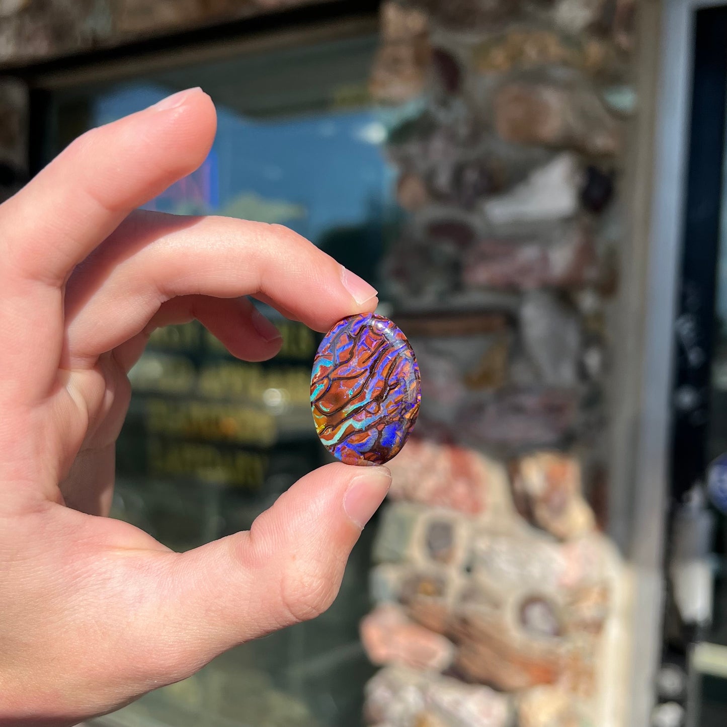 A loose, oval cabochon cut boulder opal from Koroit, Australia.  The opal has violet and purple veins.