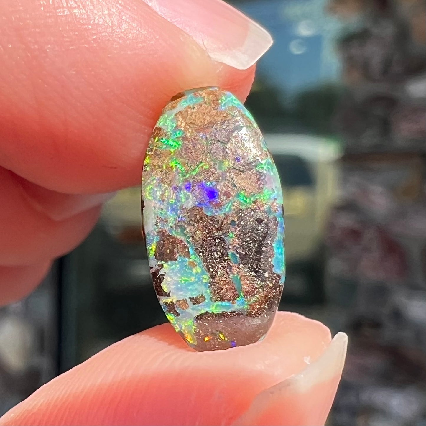 A loose, oval cabochon cut Koroit boulder opal stone.  The opal has a bright green color.