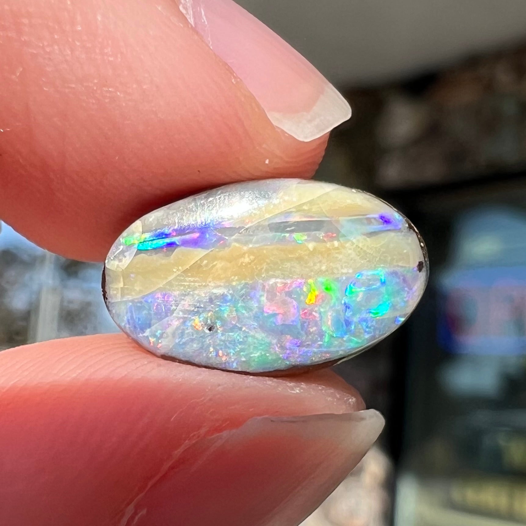 An oval cabochon cut boulder opal from Quilpie, Australia.  The opal has multicolor color play.