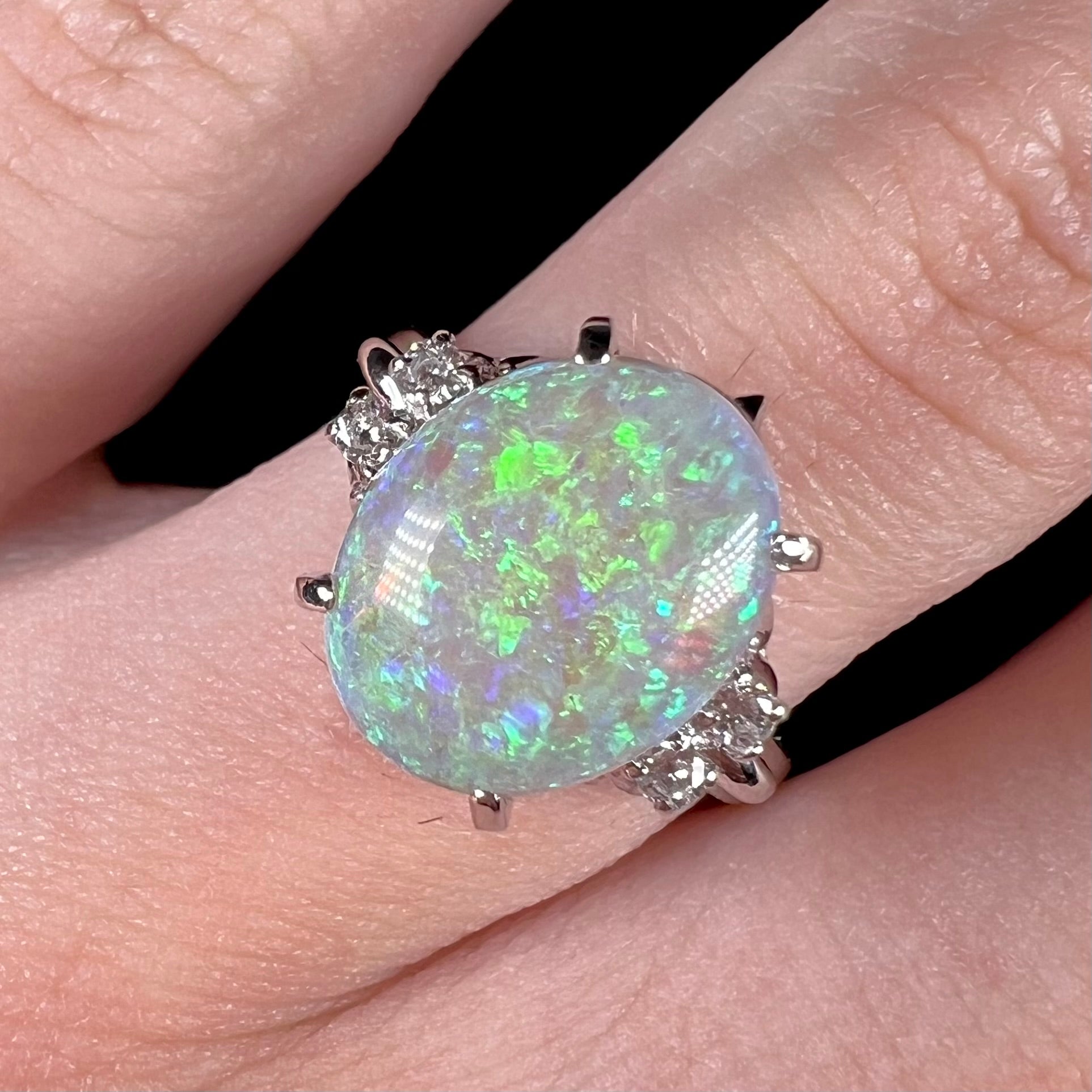 An Australian crystal opal and diamond engagement ring set in a platinum filigree mounting.  The opal plays green/blue colors and has a crack.