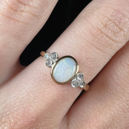 A ladies' yellow gold opal ring.  Three diamonds are set on each side of the opal.  Two rubies are set under the opal.