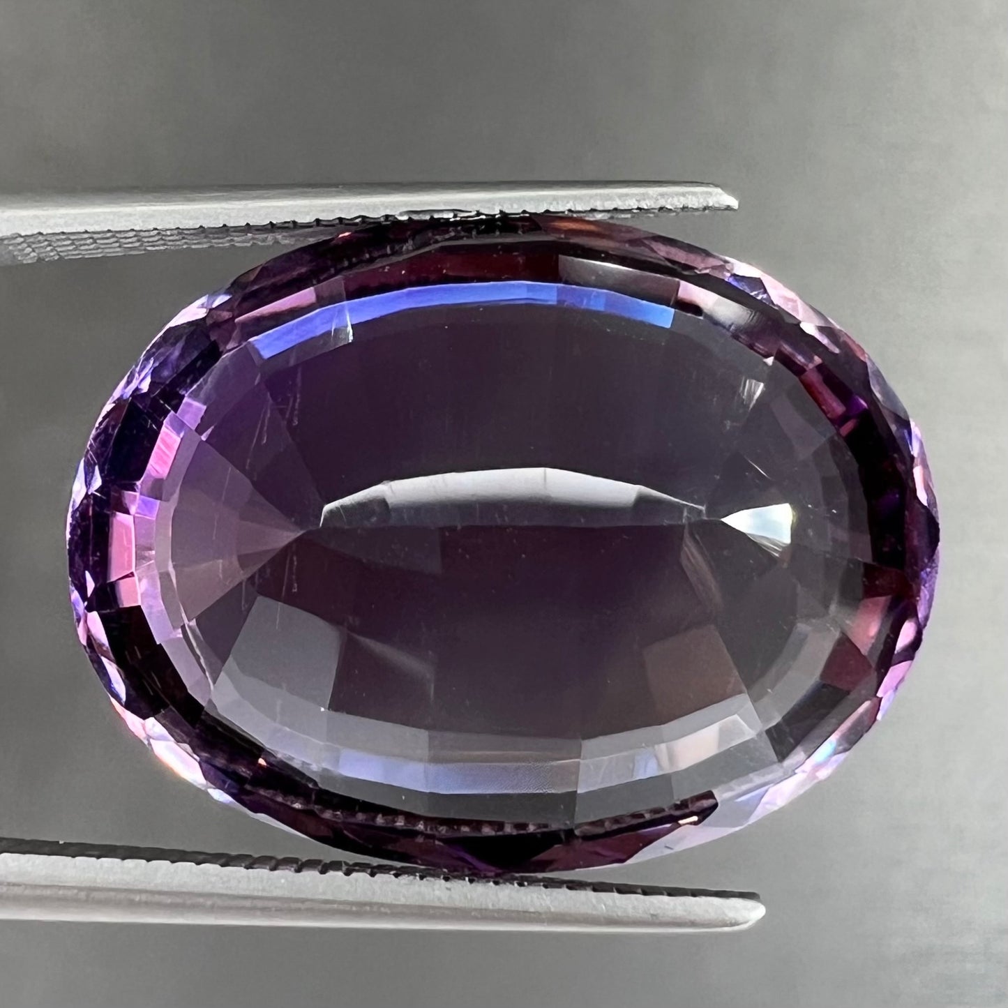 A loose, modified oval step cut amethyst gemstone.  There are light scratches to the table.