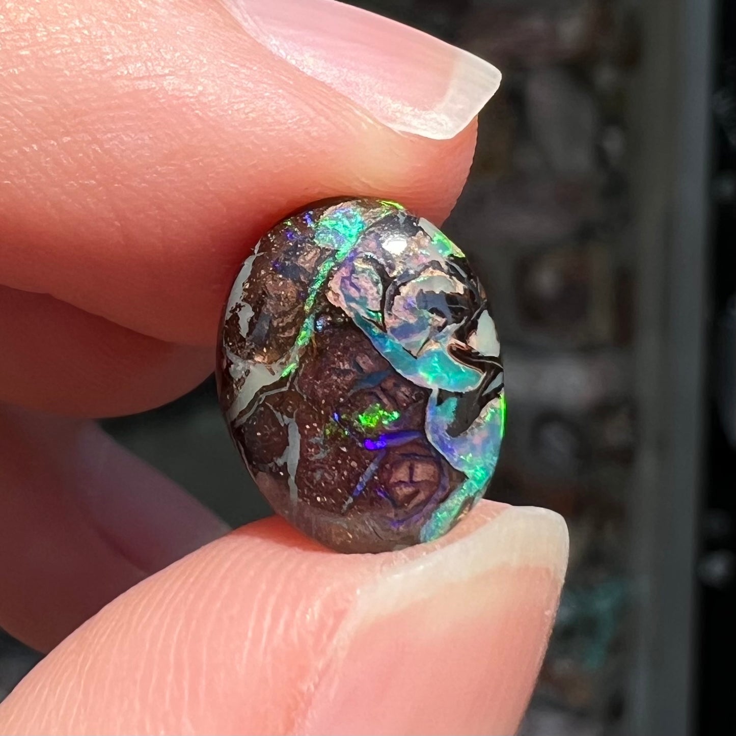 A loose, oval cabochon cut boulder opal stone from Koroit, Australia.  The opal has a bright green flash.