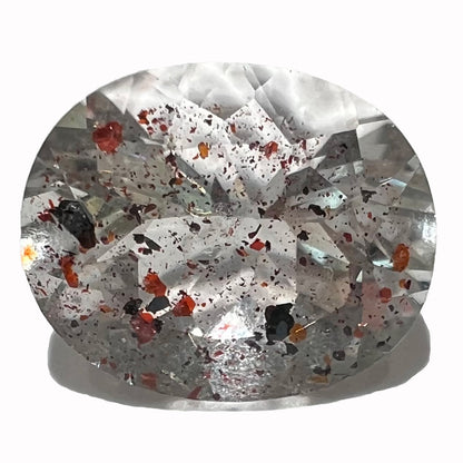 A loose, faceted oval cut lepidocrocite quartz stone.  The stone has red and black inclusions.