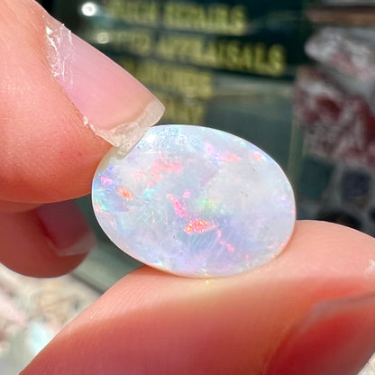 A loose oval cut opal stone from Lightning Ridge, Australia.  The opal shines pinkish red colors.