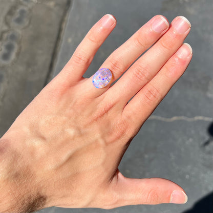 A loose, oval cabochon cut crystal opal from Lightning Ridge, Austalia that weighs 5.16 carats.  The stone has blue and purple colors.