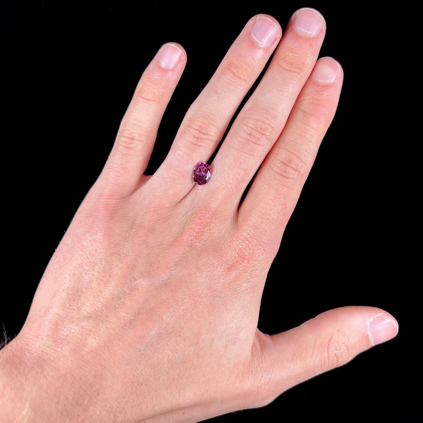 A loose, faceted oval cut purple rhodolite garnet gemstone.