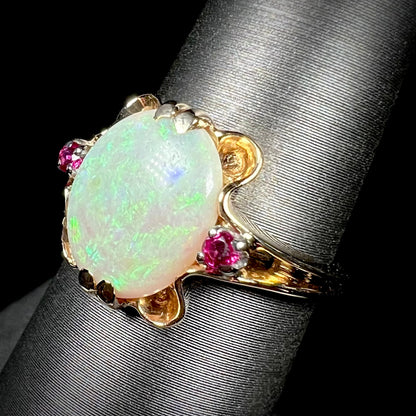 A 1920's Art Nouveau opal and pink sapphire ring.   The ring is yellow gold and palladium.  The opal is green and purple.