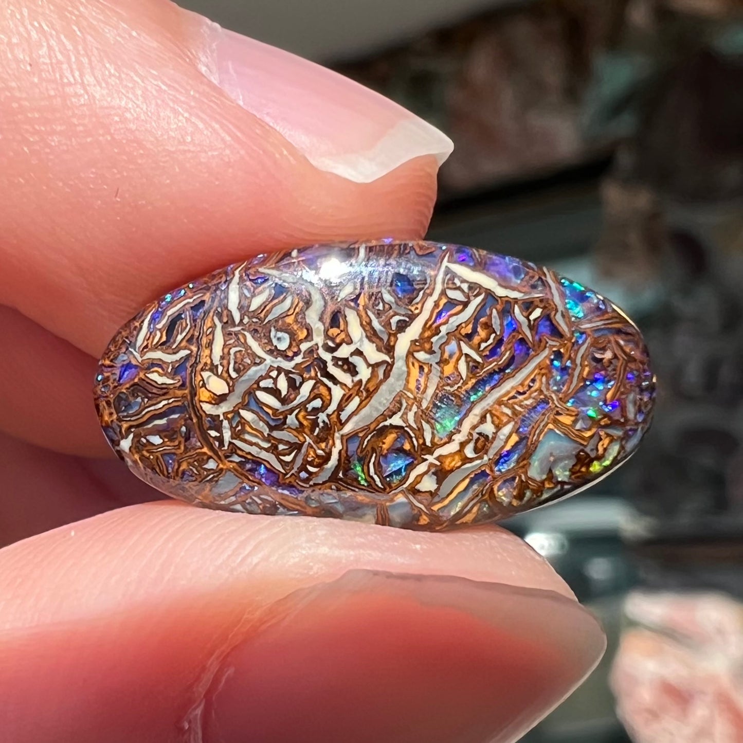 An oval cabochon cut Koroit boulder matrix opal stone.  The opal has blue colors.