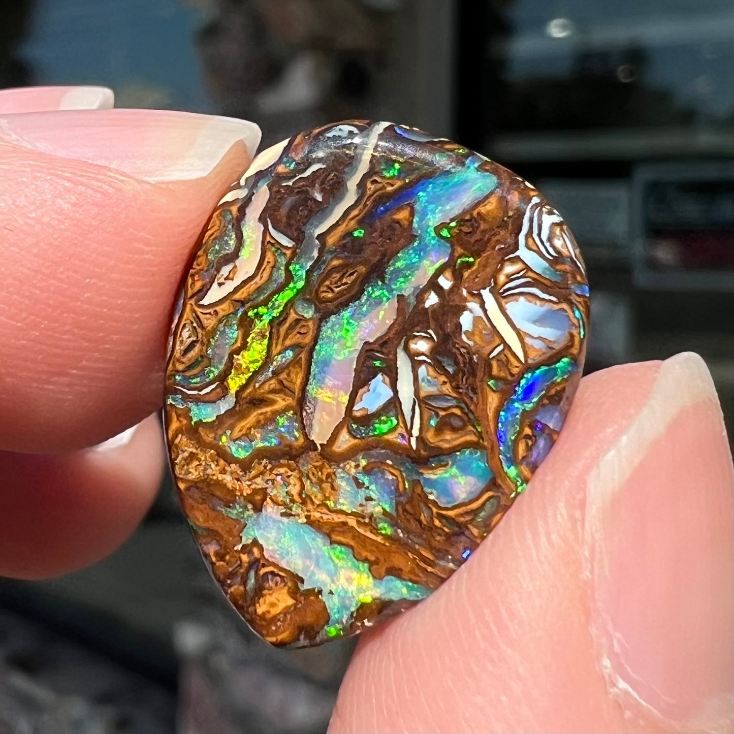 A loose, pear shaped boulder opal stone from Koroit, Australia that has vivd green and blue veins of color.