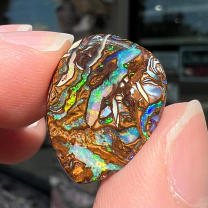 A loose, pear shaped boulder opal stone from Koroit, Australia that has vivd green and blue veins of color.