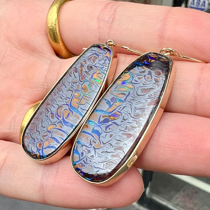 A matched pair of yellow gold patterned boulder opal dangle earrings.  The opals are from Koroit, Australia.