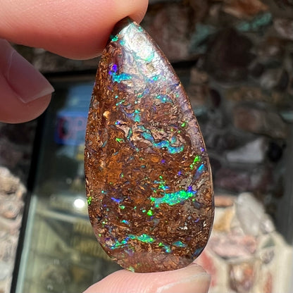 A pear shaped boulder opal stone from Koroit, Australia.  The opal has blue and green flashes.