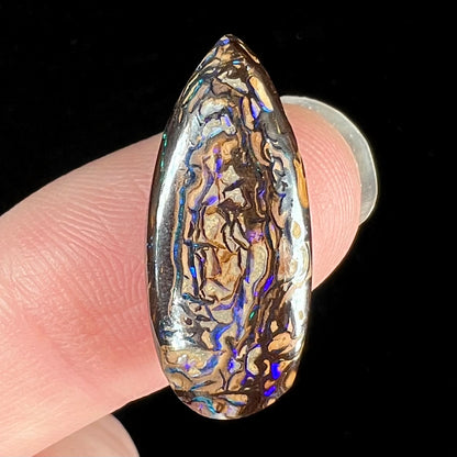 A pear shaped Koroit boulder matrix opal with blue and purple colors in veins.