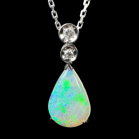 A platinum drop pendant mounted with two diamond accents and a pear shaped green-blue crystal opal.