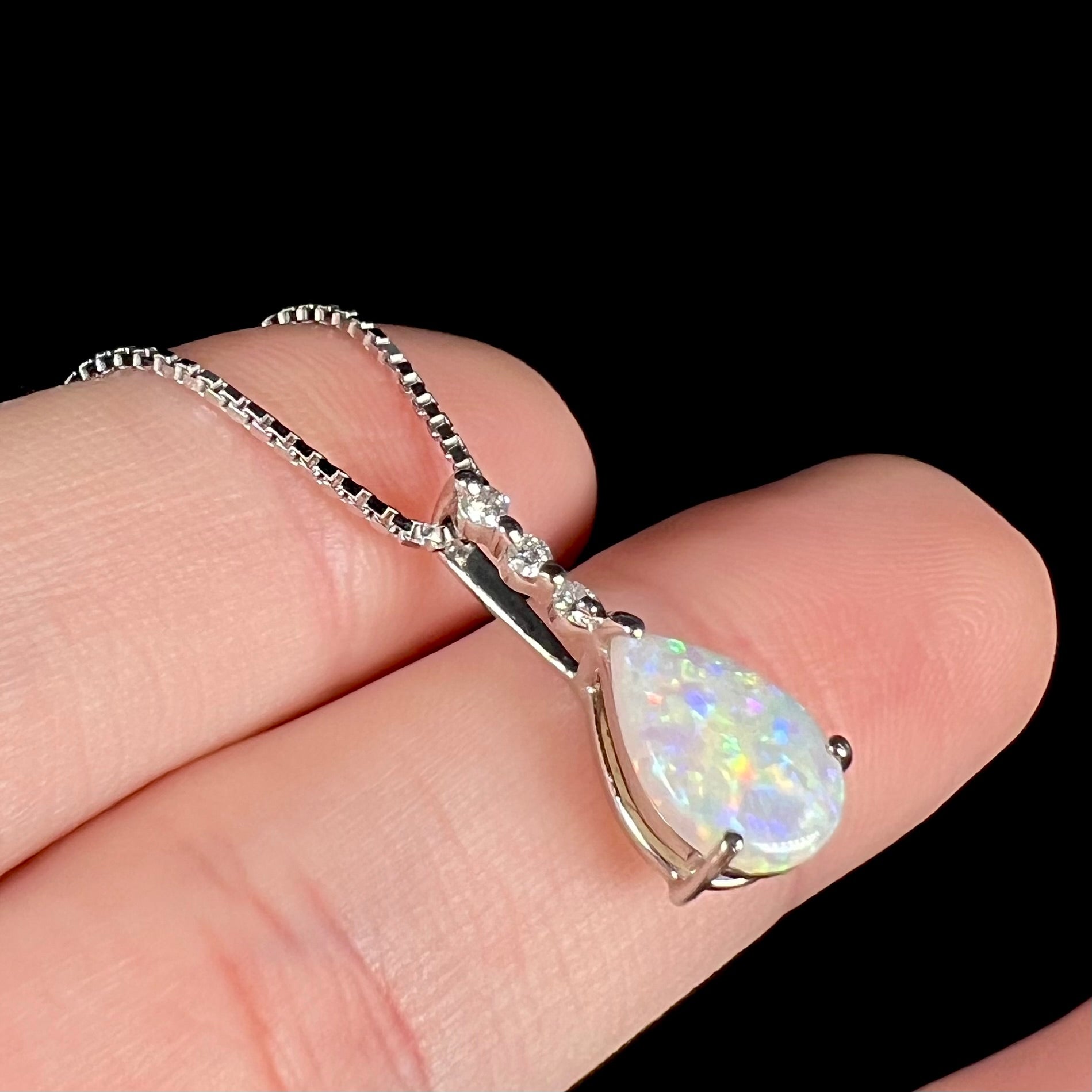 A platinum drop pendant mounted with three diamond accents and a pear shaped opal.