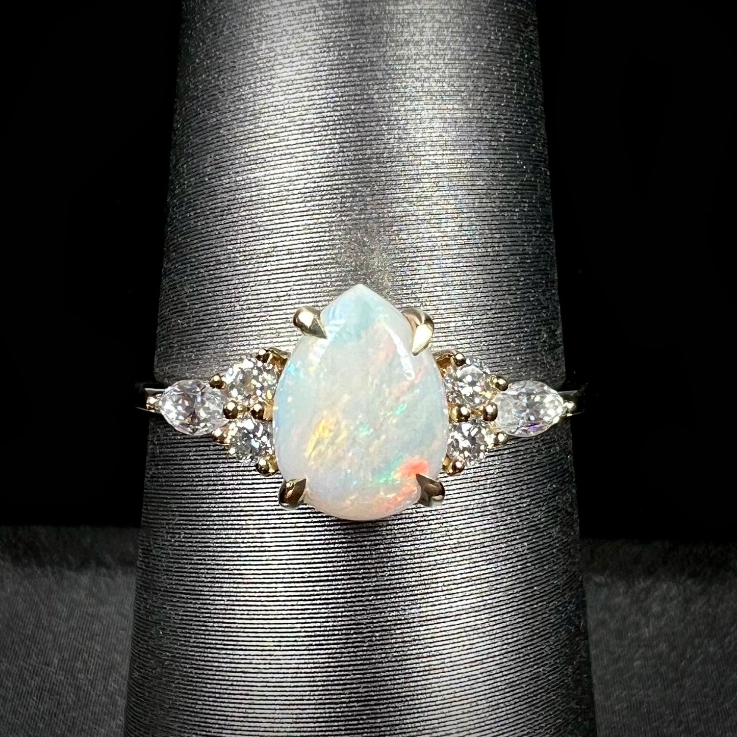 A dainty, pear shaped opal ring mounted in yellow gold with moissanite accents.