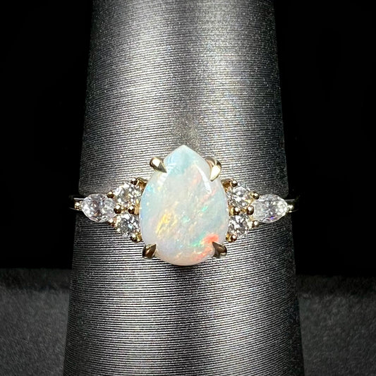 A dainty, pear shaped opal ring mounted in yellow gold with moissanite accents.