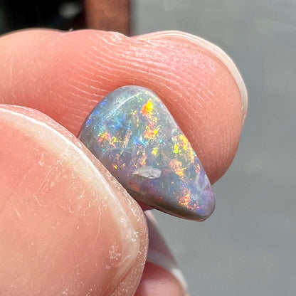 A loose, pear shaped black opal stone with red fire.