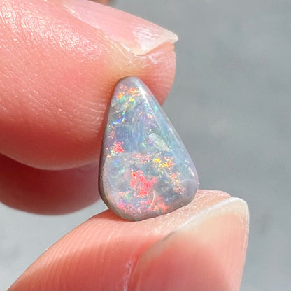 A loose, pear shaped black opal stone with red fire.