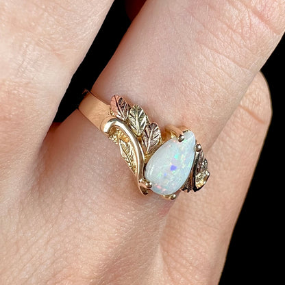 A ladies' two-tone yellow and rose Black Hills gold opal and diamond ring.  The opal is a pear shaped cabochon.