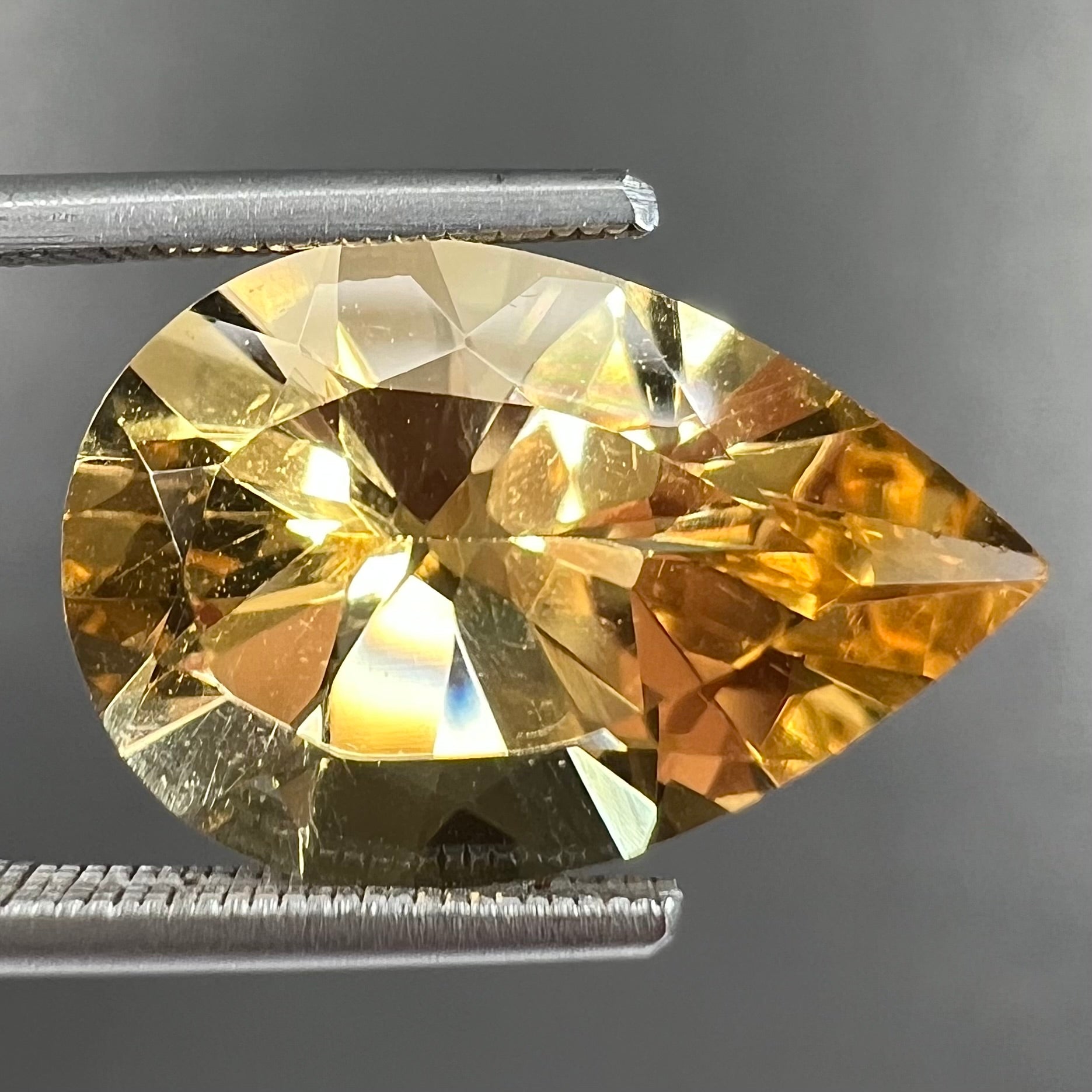 A loose, golden yellow, pear shaped citrine gemstone.