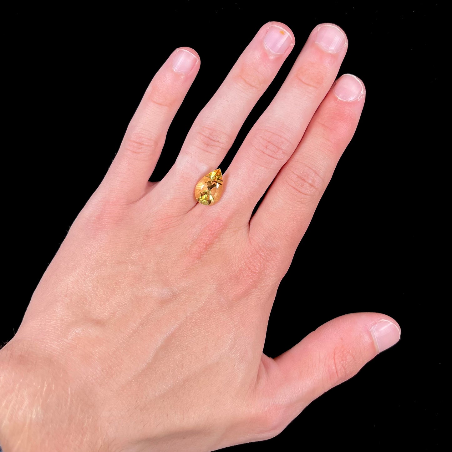 A loose, golden yellow, pear shaped citrine gemstone.