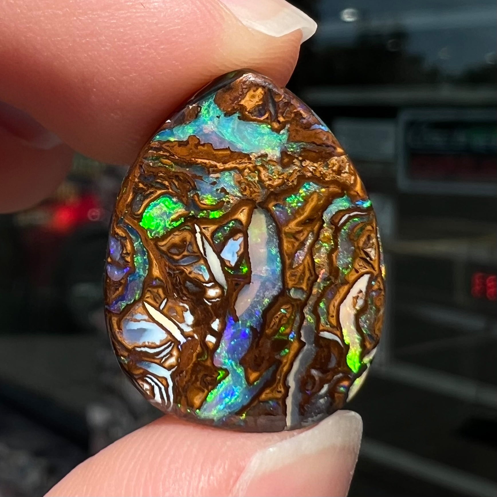 A loose, pear shaped boulder opal stone from Koroit, Australia that has vivd green and blue veins of color.