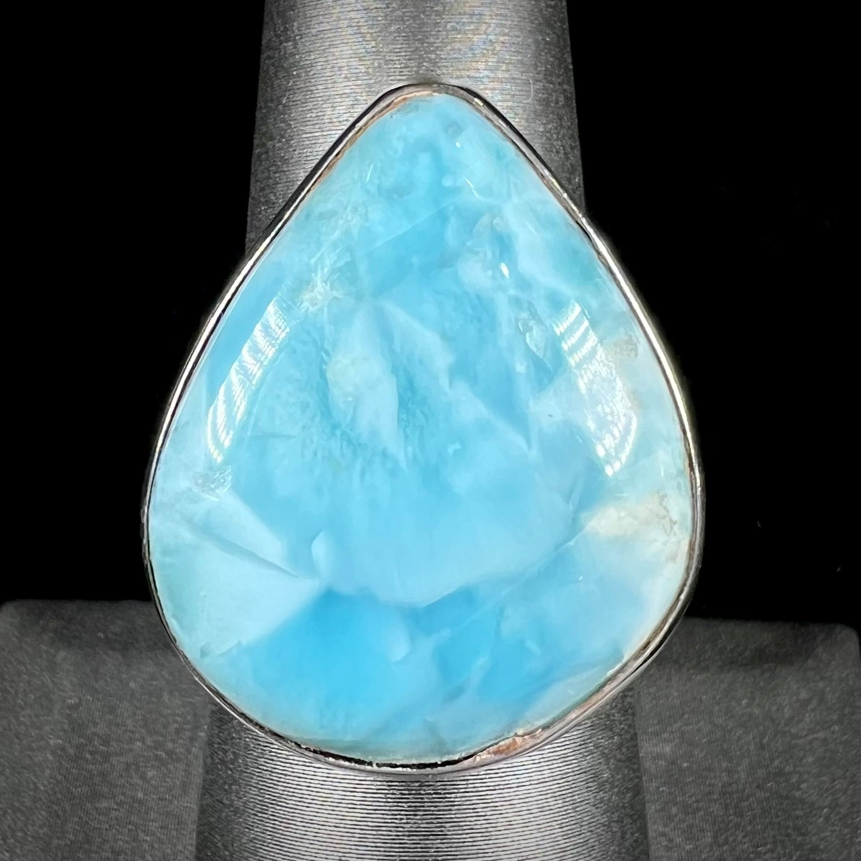 A ladies' large, pear shaped larimar solitaire ring in sterling silver.  The larimar stone measures an inch long.