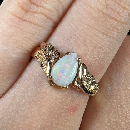 A ladies' two-tone yellow and rose Black Hills gold opal and diamond ring.  The opal is a pear shaped cabochon.