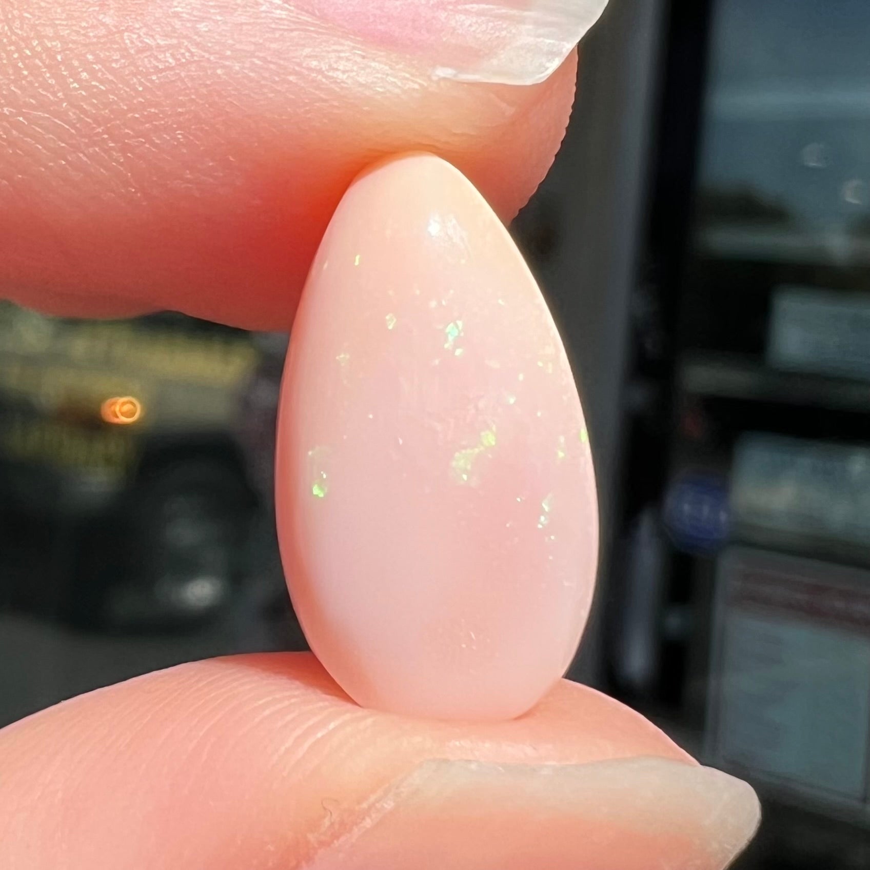 A loose, pear shaped pink Peruvian opal cabochon.  The opal has green play of color.