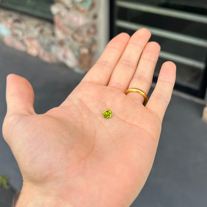 A loose, round brilliant cut peridot gemstone.