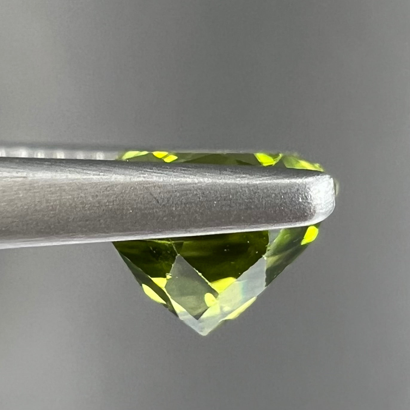 A loose, round brilliant cut peridot gemstone.