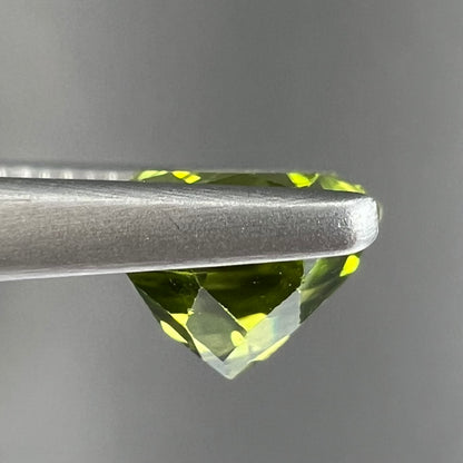 A loose, round brilliant cut peridot gemstone.