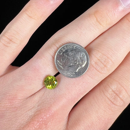 A loose, round brilliant cut peridot gemstone.