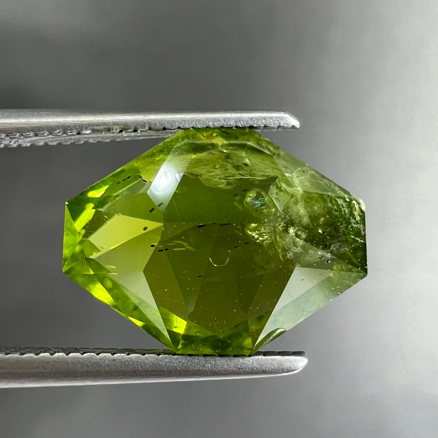 A loose, modified octagon peridot stone.  The stone is a yellow green color.