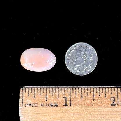 A loose, oval cabochon cut Peruvian opal stone.  The opal is a coral pink color.